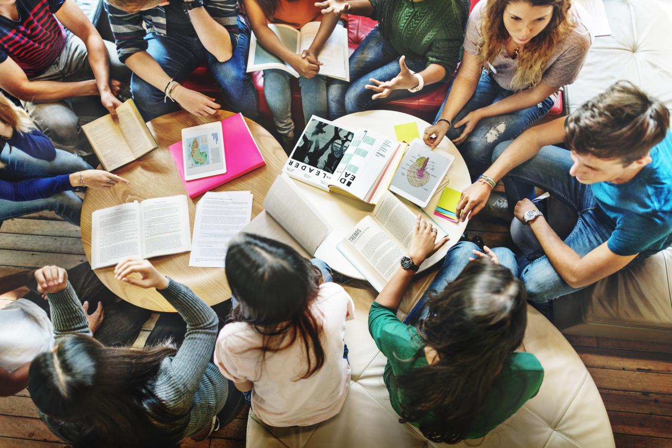 People sitting around a table with books on it.